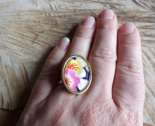 Bague cabochon ovale de 18x25mm - papier japonais fleurs jaunes et roses, fond bleu - acier inoxydable doré